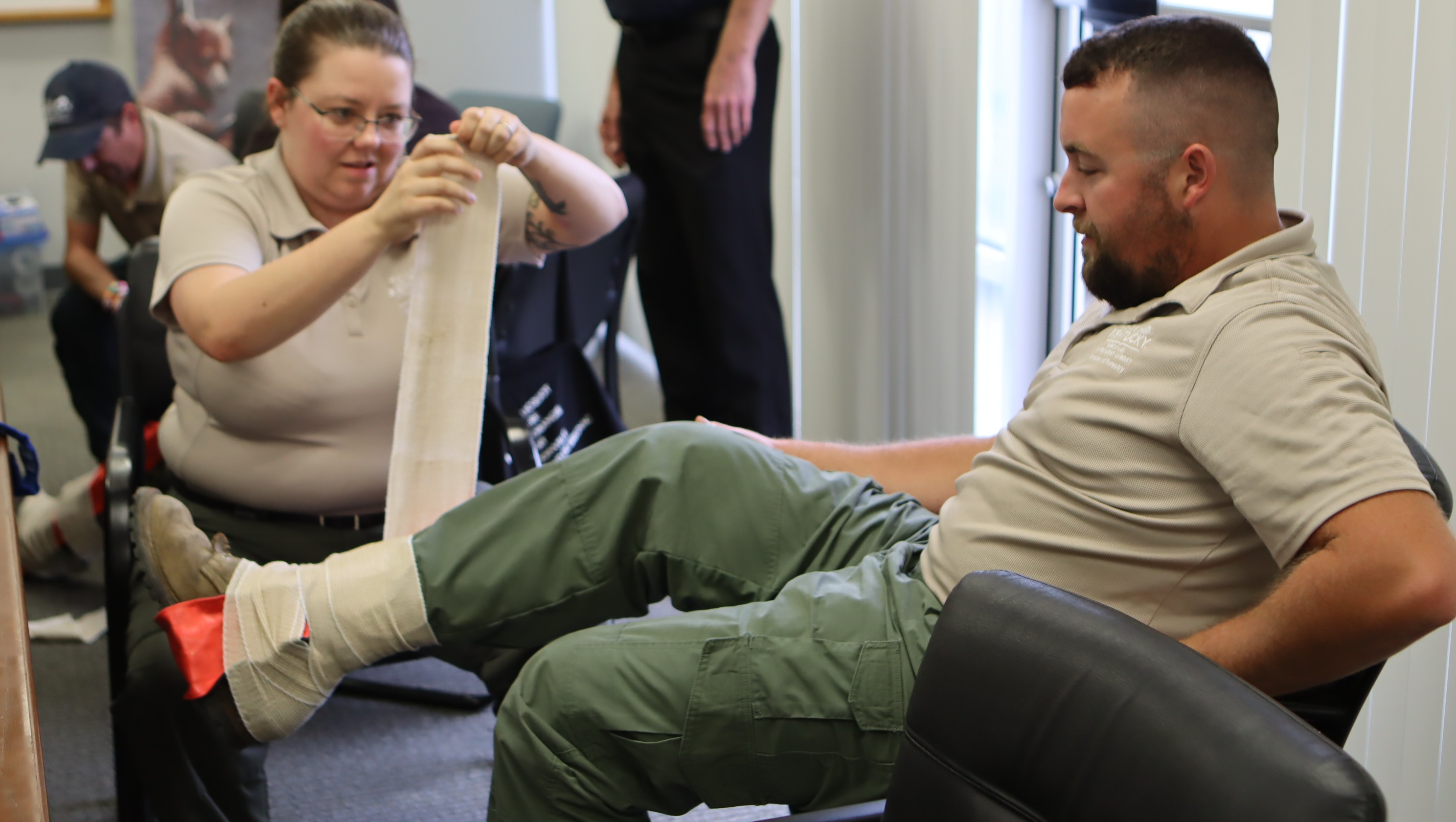 A coworker practices an ankle splint on a coworker. 