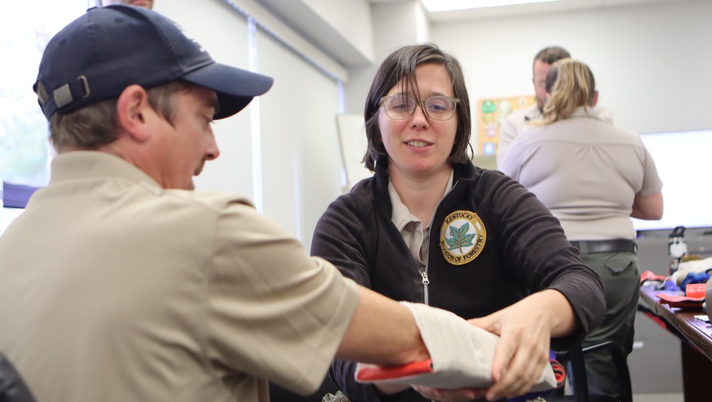 A woman is bandaging another employees arm in an arm splint training exercise. 