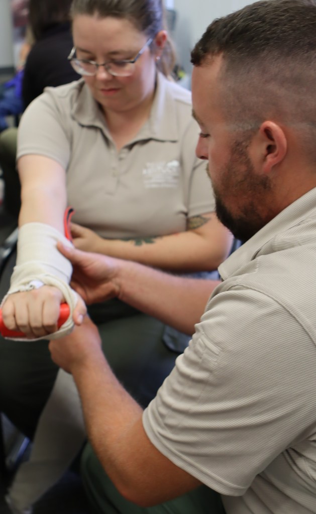 A man practices his arm splint on a co-worker. 