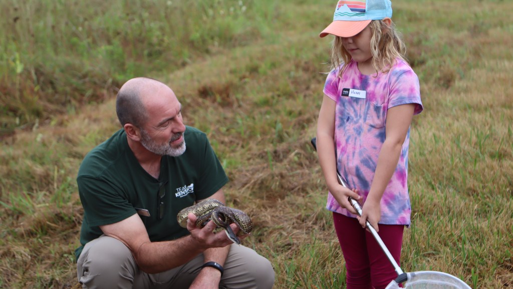 State Parks Naturalist Robert Myers talks about a snake found at the site to a young attendee. 